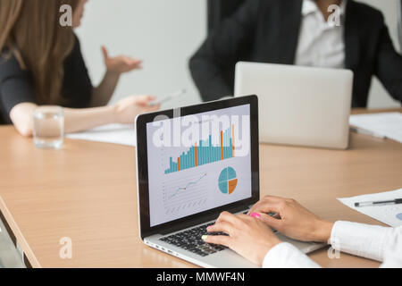 African businesswoman analyzing statistics on laptop at group me Stock Photo