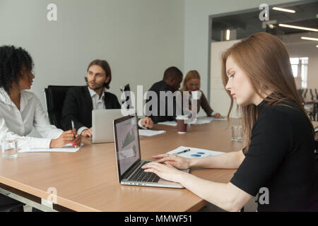 Female project manager working on laptop at meeting analyzing st Stock Photo