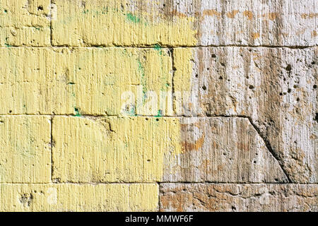 Image of a wall made of brown stone, painted half yellow, for use as a background. Stock Photo
