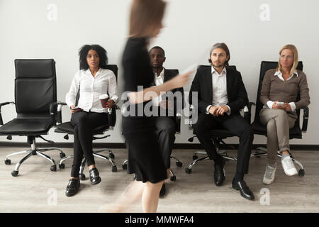 Stressed applicants sitting in queue watching rival after job in Stock Photo