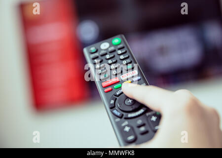 WROCLAW, POLAND - APRIL 03rd, 2018: Woman's hand is holding a TV remote control with streaming media services. Streaming media is multimedia that is c Stock Photo