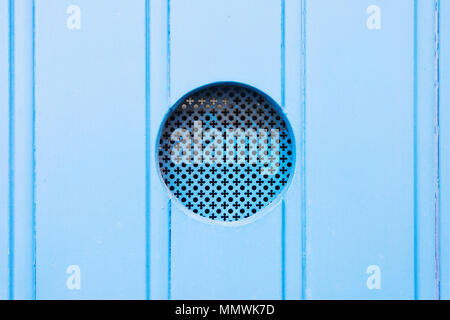 Leuca, Apulia, Italy - A traditional old metal peephole in a blue wooden door Stock Photo