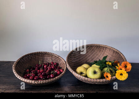 cerries apples and flowers in two baskets Stock Photo