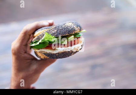 Man holding a delicious cream cheese and salmon bagel Stock Photo