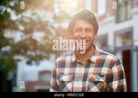 Smiling young man standing on a city street in summer Stock Photo