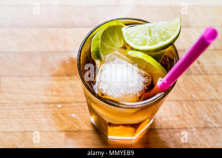 Long island iced tea cocktail with lime, ice and served with pink straw. Beverage concept. Stock Photo