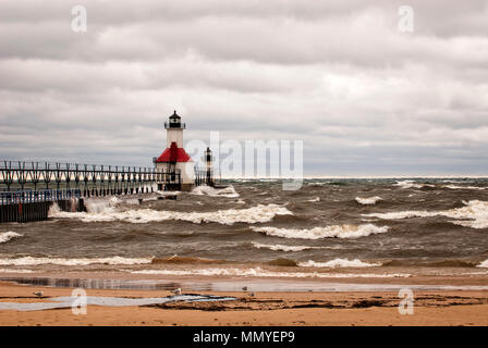 A small lighthouse out on a pier in St. Joeseph Michigan during stromy weather with waves crashing into the pier. Stock Photo