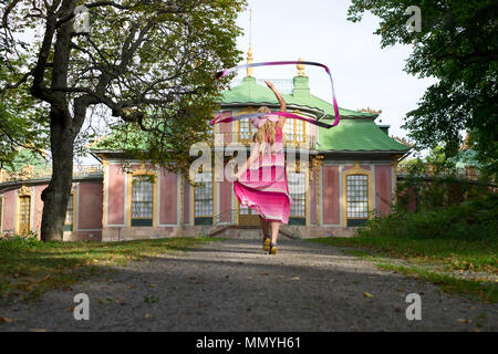 Happy girl dancing on the road to the Chinese Pavilion at the Drottningholm Park. The pavilion is currently a UNESCO  World Heritage site. Stock Photo