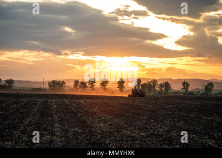 Farming tractor plowing and spraying on field. Stock Photo