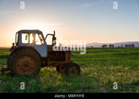 Farming tractor plowing and spraying on field. Stock Photo