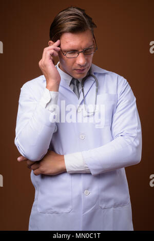 Studio shot of man doctor against brown background Stock Photo