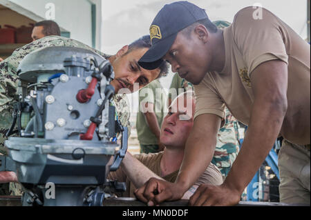 U.S. Navy Engineman 2nd Class Noah Edwards and Chief Boatswain's Mate Robert Roy, both assigned to Coastal Riverine Group 1, troubleshoot a boat engine with Timor-Leste National Police Agent Jeferino Gomes during Cooperation Afloat Readiness and Training (CARAT) Timor-Leste 2017 at Port Hera Naval Base, Timor-Leste, Aug. 2, 2017. CARAT is a bilateral exercise series between the U.S. Navy and the armed forces of eight partner nations in South and Southeast Asia which contributes to regional security and stability by providing a credible venue to share best practices and practice cooperation in  Stock Photo