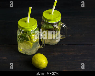 Mojito cocktail with lime slices and mint in a jar on a dark wooden background. Summer non-alcoholic drink Stock Photo