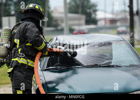A firefighter from the 788th Civil Engineer Fire Department hoses down the inside of a car which is supposed to be on fire on the scene of a simulated major crash during a base exercise at Wright-Patterson Air Force Base, Ohio, Aug. 4, 2017. Readiness exercises are routinely held to streamline unit cohesion when responding to emergencies. (U.S. Air Force photo by Wesley Farnsworth/Released) Stock Photo
