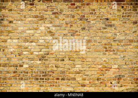 Old and weathered grungy yellow and red brick wall as seamless pattern texture background. Stock Photo