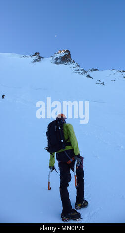 male mountain climber at the start of a steep north face route just before dawn in the Italian Alps near Aosta Stock Photo