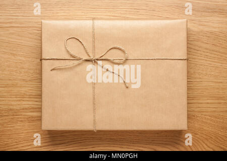 Big gift box with bow wrapped in kraft paper on wooden table Stock Photo