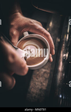 Barista pours milk making cappuccino or latte art. Toned picture Stock Photo