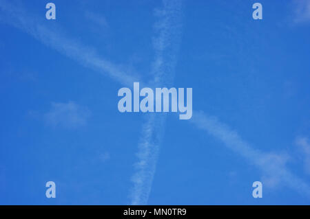 Plane traces in x shape with  little veil clouds Stock Photo