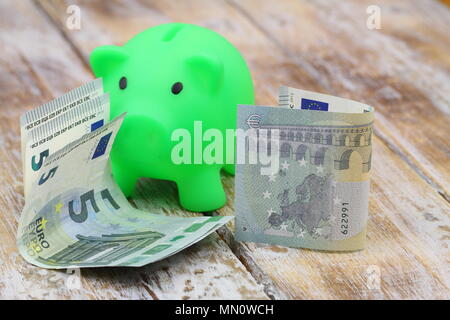 Two five Euro notes with piggy bank on rustic wooden surface Stock Photo