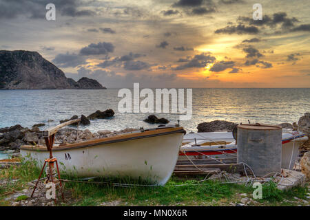 Sunset over the Ionian sea near Petani on the Greek island Kefalonia, in the foreground small fishing boats pulled out of the water Stock Photo