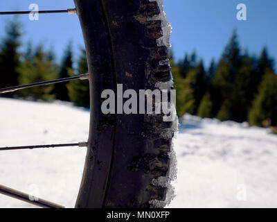 Cycling on large tyres in fresh snow. Biker goes by bike on the snowy road in the mountains. Picture taken in HDR mode. Stock Photo