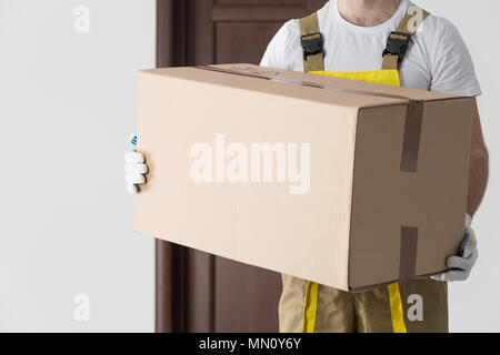 Delivery man with big box close-up. Professional moving goods background. Stock Photo