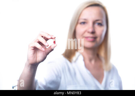 Smiling woman shows a capsule tablet. Focus on the capsule. White background Stock Photo