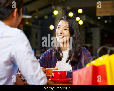 young asian couple lovers sitting at table chatting talking in coffee shop after shopping. Stock Photo