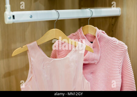 A row of children clothes hanging on hangers. Fashion for girls.Wardrobe with kid clothes.wooden Hangers with pink clothes. Set for girl Stock Photo