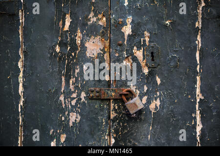 Wooden dark grey door background locked with rusty padlock. Timeworn entrance provides safety and privacy. Close up view with details. Stock Photo