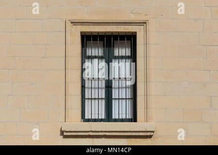 Malta, Valletta. Facade of yellow limestone house with closed window with metal grid, that provides security. Close up view. Stock Photo