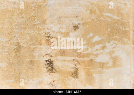 Weathered yellow painted wall background, partially faded. Corroded, peeled, vintage, blank wall for backdrop. Close up view with details. Stock Photo