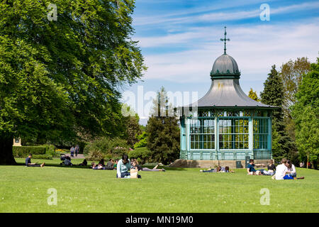 People sat in Weston Park, Sheffield, UK on a sunny day, next to an old bandstand. Stock Photo