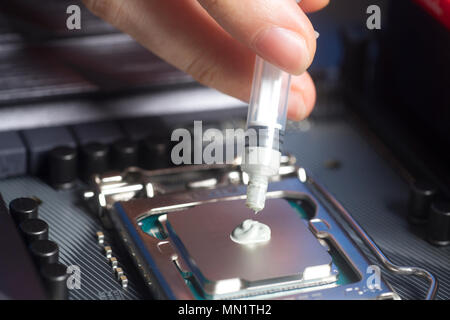 Hand wearing White Gloves with syringe applying thermal paste on the CPU processor on motherboard Close up Stock Photo