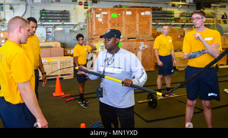 MAYPORT, Fla. (August 10, 2017) Sailors receive training on gym equipment from Master Chief Aviation Boatswain’s Mate Glen Newbins prior to the unveiling of the new mobile gym in the hanger bay aboard the amphibious assault ship USS Iwo Jima (LHD 7). Iwo Jima is in port conducting a scheduled continuous maintenance availability in preparation for their upcoming deployment. (U.S. Navy photo by Mass Communication Specialist Seaman Joe J. Cardona Gonzalez/Released) Stock Photo