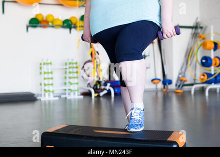 Low section portrait of  unrecognizable obese woman doing step exercises during weight loss training in gym, copy space Stock Photo
