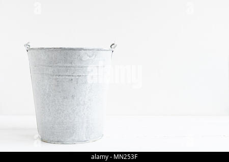 Aluminum metal bucket on white wooden table with place for text. Copy space. Stock Photo