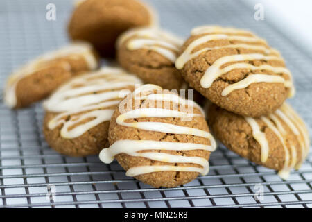 Freshly baked, homemade pumpkin spice cookies, with maple icing. These gluten and dairy free biscuits are displayed on a wire cooling. Stock Photo