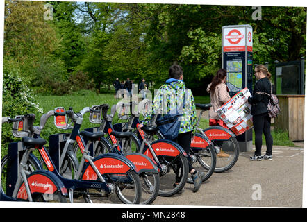 Tourists choose a bike to hire at a docking station in central London , Kensington park Stock Photo