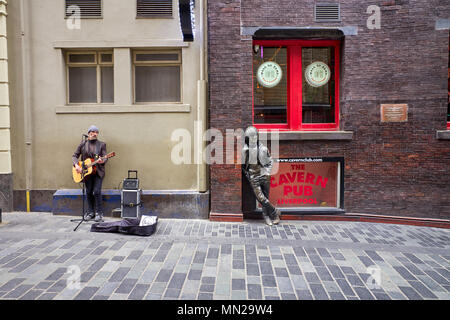 The Busker in Matthew Street, Liverpool next to statue of John Lennon and the wall of fame bricks Stock Photo