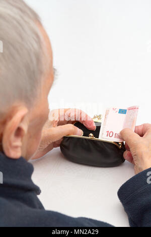 Senior woman holding an empty purse and a ten Euro banknote in her hands., copy or text space, old-age poverty concept Stock Photo