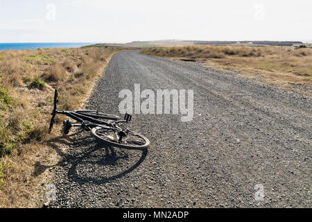 Bicycle along a gravel road a the Nobbies with dry grass landscape, Phillip Island, Victoria, Australia Stock Photo