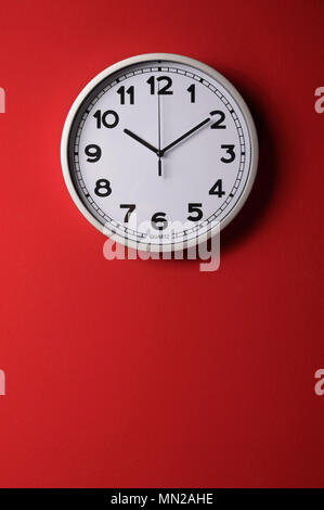 Clock on the red wall showing ten and ten Stock Photo