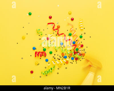 Party spray on yellow background. Bright creative background with explosion of serpentine, confetti and candies. Conceptual minimalism. Stock Photo