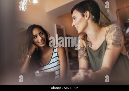 Friends talking while sitting at home with a fruit bowl on the table. Two women bloggers sharing ideas on flood blogging. Stock Photo