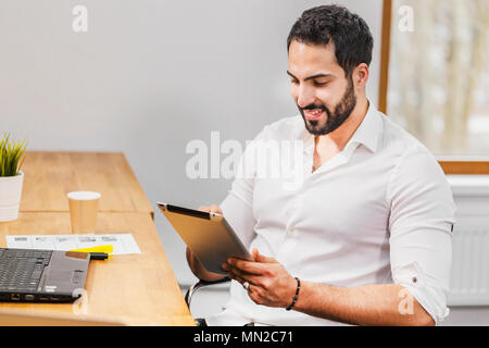 Closeup of man using tablet, touching computer screen while working in cozy office Stock Photo