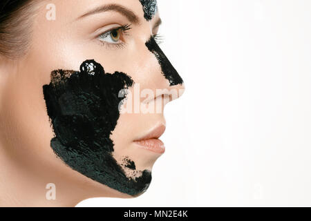 Young beautiful woman applying a mask for the face of the therapeutic black mud. Spa treatment Stock Photo