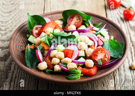 Chickpears and  fresh vegetables salad in ceramic bowl, healthy  vegan meal on rustic wooden table Stock Photo