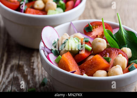 Chickpears and  fresh vegetables salad in ceramic bowl, healthy  vegan meal on rustic wooden table Stock Photo